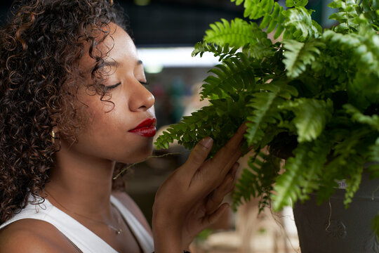 Young woman smelling fern