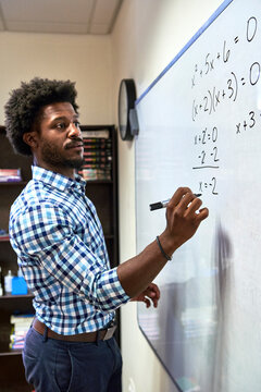 Maths teacher writing a formula on a whiteboard