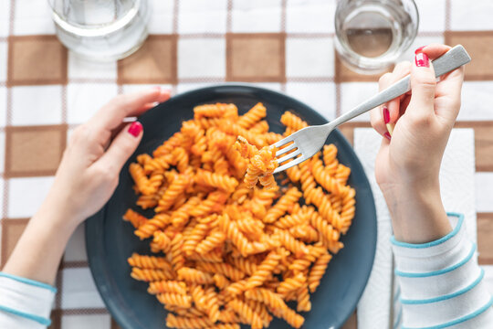 Woman eating pasta at dining table at home