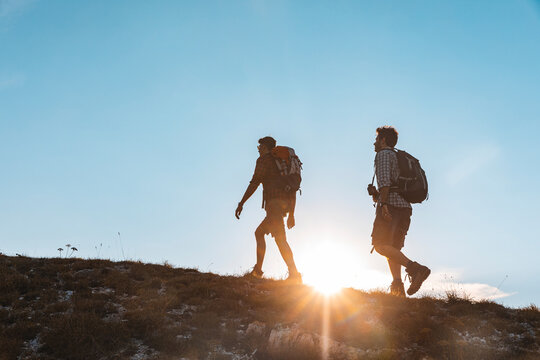 Italy, Monte Nerone, two men hiking in mountains at sunset