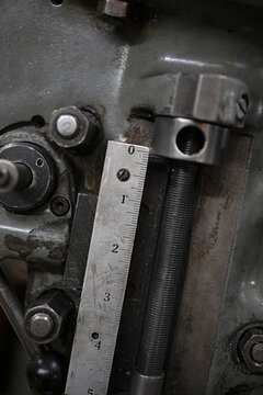 Close-up of a metal ruler measuring the precise movement of a threaded rod on industrial machinery