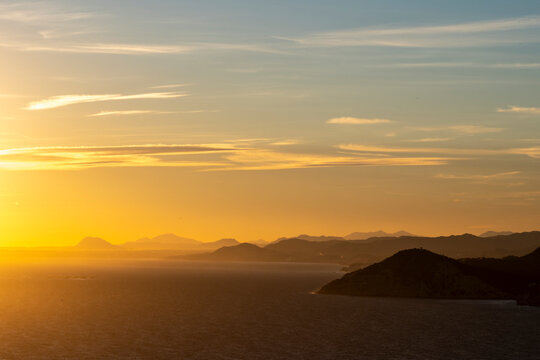 Coastal travel landscape near Benidorm Spain with sea and coastline under a golden sunset sky as the horizon glows in calm evening light and color