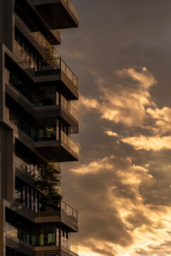 Dramatic golden sunset sky with towering clouds framing a modern urban skyline as a city building facade and architecture silhouette rises above