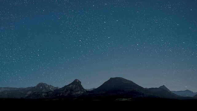 movement of stars in the night sky with the view of mountains.