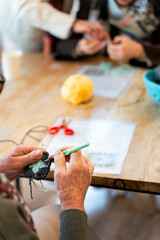 Senior hands crocheting yarn in knitting club workshop