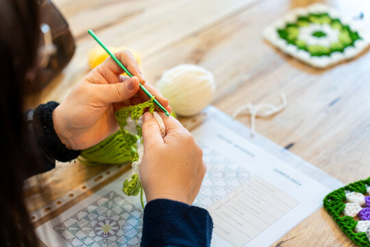 Person crocheting granny square following pattern instructions