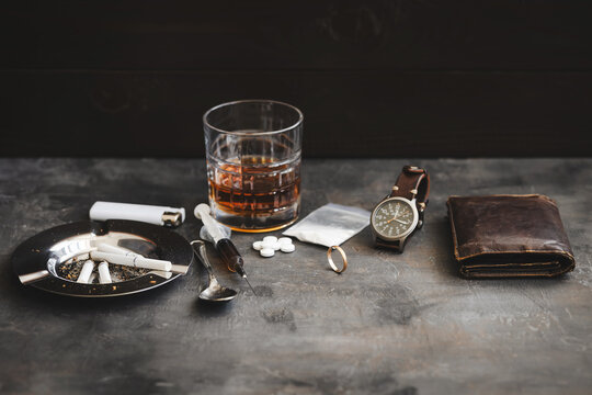 Drug and alcohol addiction concept with heroin syringe, cocaine, pills and wedding ring on wooden table, substance abuse destroying marriage and life
