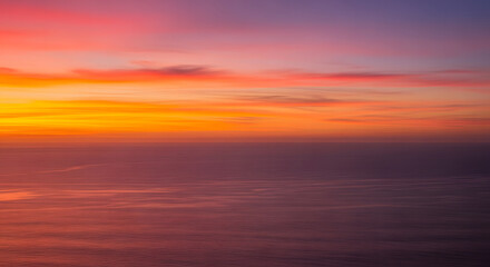 Fototapeta premium Sunrise over the ocean horizon with vibrant orange and pink clou