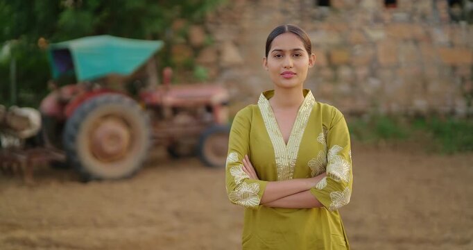 Indian young adult gen z villager female expert staff fold hand look camera standing visit rural area. Happy proud girl officer cross arm staring cam do casual pose enjoy new day village ground place
