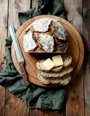 Handwerklich hergestellte Sauerteigbrotscheiben mit Butter auf einem runden Holzbrett.Draufsicht