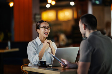 Business colleagues laughing during a casual coffee shop meeting