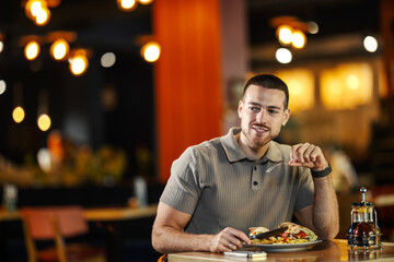 Young adult man enjoying solo meal at restaurant