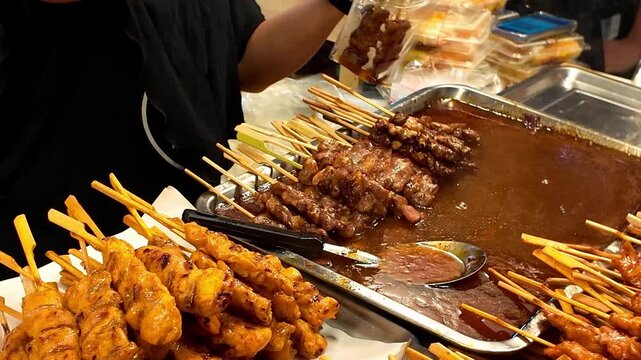 Thai Street Food Skewers Being Dipped In Rich Peanut Sauce