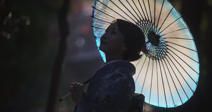 Cinematic silhouette of woman in kimono holding glowing umbrella - slow motion