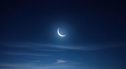 Slender crescent moon glowing brightly in a deep indigo night sky with subtle cloud streaks. The celestial body emits a soft, ethereal light against the dark, expansive backdrop.