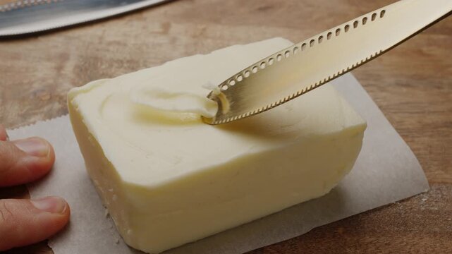 Close-up of a butter curler scraping a fresh block of butter into curls.