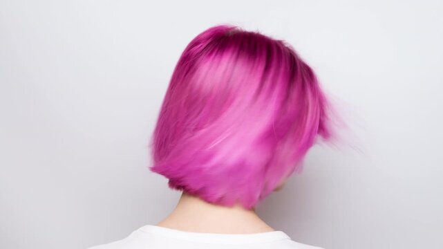 Young woman shows off pink hair and hairstyle by turning her head.