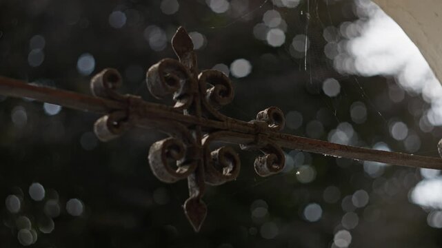 Vintage Raindrenched Ornament. Moody Cinematic Scene Featuring Vintage Patina And Textured Decay. Aged Garden Gate With Dripping Droplets Illuminated By Bokeh Lights In Rainy Weather