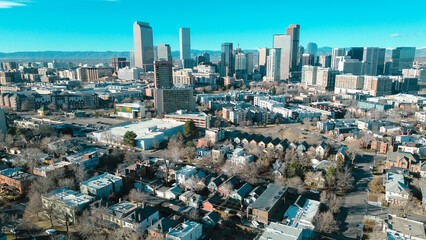 Historic core neighborhoods west of Cheesman Park toward glass towers, downtown skylines, mountain range near Franklin St. Mixed rooflines, muted foliage, varied exterior tones in Denver, CO