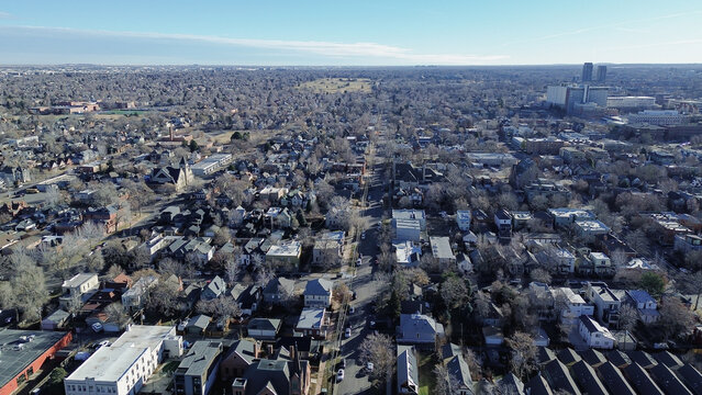 Residential&ndash;urban merge over streets near City Park West transition toward commercial corridors along York St. Mixed roofing, subdued winter vegetation and textured facades, Denver, Colorado