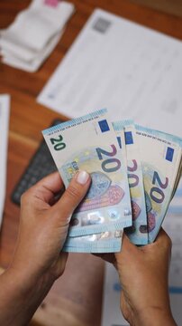 Female hands count euros while sitting at a table. Utility bills and receipts on the table. The process of calculating a household budget. Or the process of calculating the income of a small business.