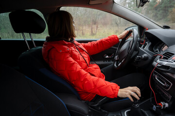 Young Woman in Red Puffer Jacket Driving a Car on an Autumn Road Trip - Side View Profile © dizfoto1973
