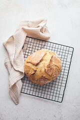 Round sourdough loaf resting on black wire cooling rack with beige linen towel. Perfect for baking, food blogs, and culinary projects