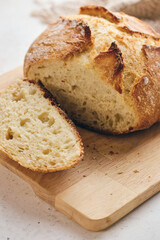 Sliced artisan sourdough bread with airy crumb on wooden board, glass of milk, and knitted cloth. Ideal for culinary, baking, and food photography projects.