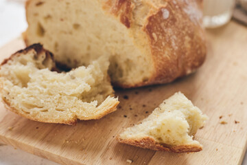 Sliced artisan sourdough bread with airy crumb on wooden board, glass of milk, and knitted cloth. Ideal for culinary, baking, and food photography projects.