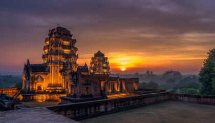 Ancient temple complex illuminated at sunset with lush surroundings.