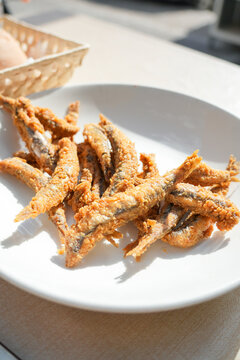 A plate of fried fish with a basket in the background