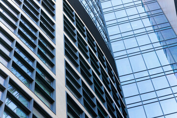 Obraz premium Modern glass skyscraper facade with geometric patterns and reflections close up perspective urban sky line view from below