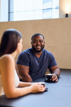 Smiling African-American Man Converses With Woman Over Coffee in a Modern Caf&eacute; Setting