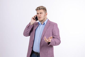 Naklejka premium Stylish man in pink blazer talking on mobile phone in studio