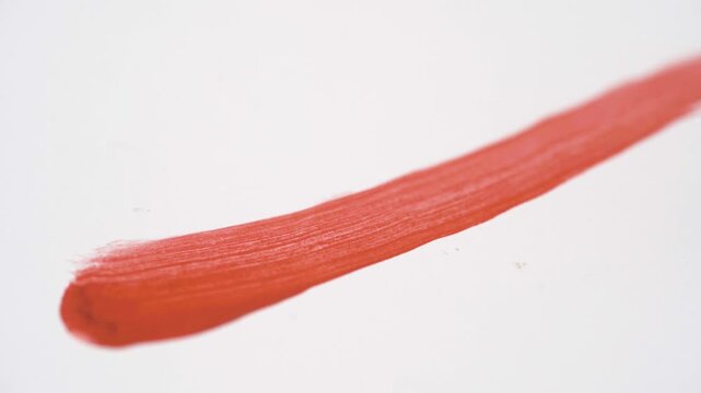 Painting red lipstick brush stroke texture on white background. makeup swatch. Cosmetic product smudge