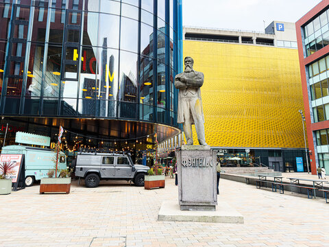 Manchester UK square scene with Friedrich Engels statue, First Street Car Park modern architecture, and vibrant plaza in city center