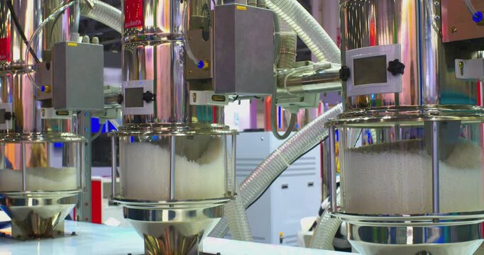 An automated industrial machine mixes plastic granules in a controlled environment for consistent quality output. The process showcases precision engineering and efficient manufacturing techniques to 