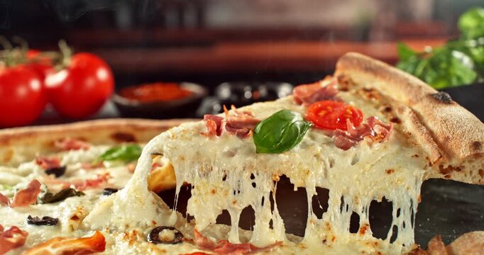 Super slow motion footage (1000 fps) of a pizza slice being lifted with perfectly melted, stretchy cheese. Rich textures of crust, prosciutto, tomato and fresh basil in cinematic light.
