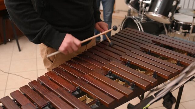 A close-up of a teenager playing a wooden xylophone. Drums lesson at a music school. Closeup no face