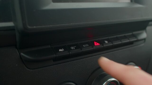 Pressing button near hazard light indicator, Closeup of hand pressing dashboard hazard control button, Detailed view of finger activating dashboard hazard light button with feedback 