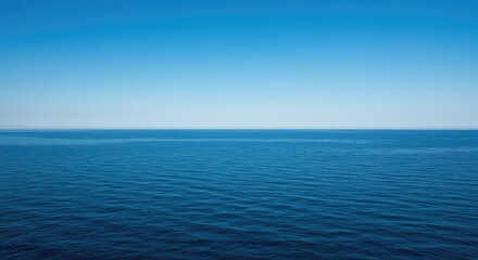 Obraz premium A massive expanse of deep blue water stretches endlessly toward the distant horizon under a clear sky, symbolizing travel and freedom ,abstract ,boundless ,nature
