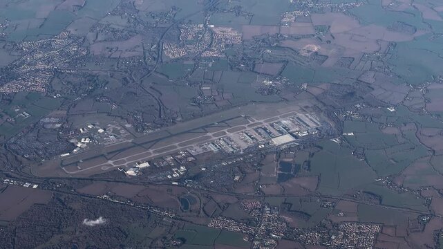flying across Essex in United Kingdom with landscape around Stansted Airport  International Airport (IATA: STN, ICAO: EGSS) with runway, taxi ways and terminal buildings - 4k aerial video footage