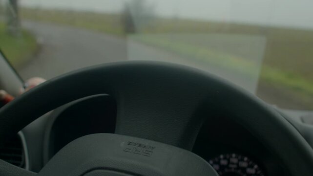 Steady hands navigate through foggy fields, Focused driver keeps control during misty rural exploration, Calmly steering through foggy rural landscape with firm grip on steering wheel 