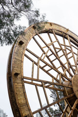 Giant Wooden Water Wheel Structure Under Cloudy Sky, Outdoor Art Installation