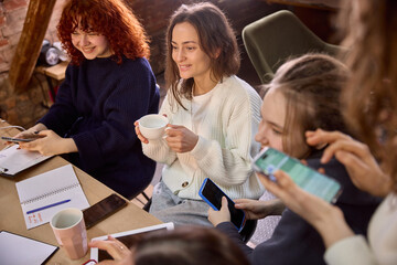 Women colleagues checking mobile analytics during strategy session. Concept of sales dashboard...