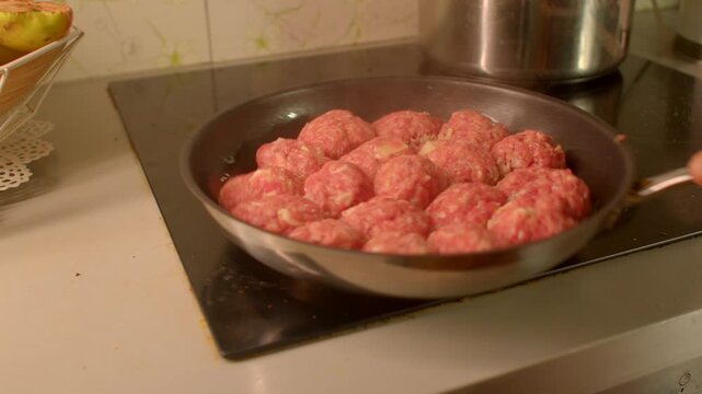 Uncooked meatballs preparing, Home chef arranging raw meat mixture, Closeup of raw beef and pork meatballs on stove, Preparing fresh raw meatballs in skillet for family meal tonight 