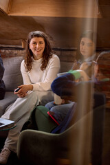 Young professional woman smiling during informal team meeting on sofa. Concept of startup culture,...