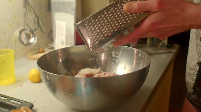 Candid kitchen with grated binder, Living cooking environment with fresh ingredients and utensils, Authentic kitchen scene featuring woman grating binder into bowl with kitchen tools 
