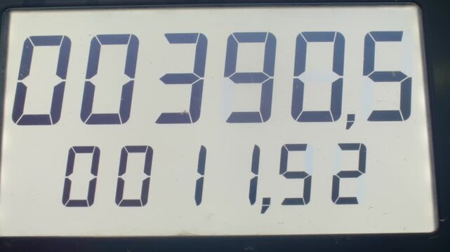 digital meter display showing changing readings, closeup lcd digits cycling through totals and decimals, mechanic checks odometer during maintenance, fleet manager audits consumption logs, technician