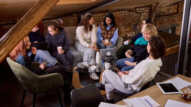 Large women team gathered around table for collaborative office meeting. Concept of inclusive leadership session, cross functional strategy planning, startup teamwork, modern business environment.